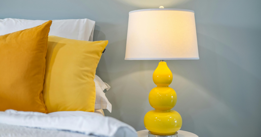 Close-up of yellow themed bedroom pillows and bedside lamp