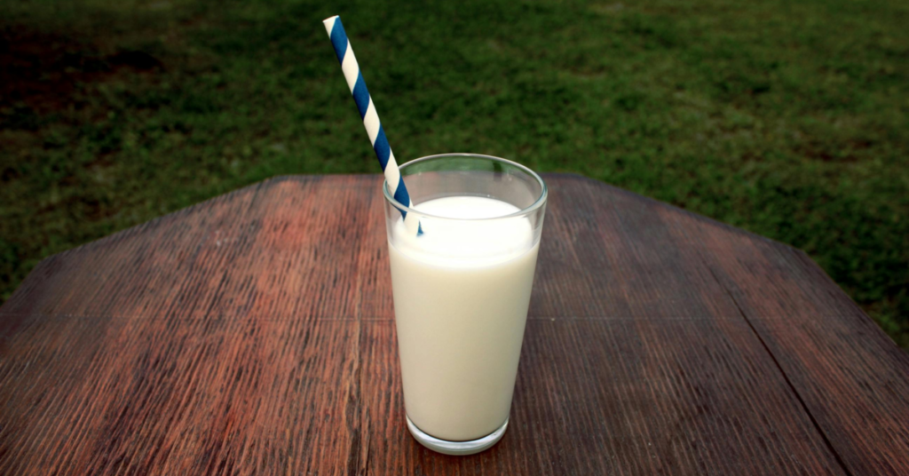 Glass of milk outside on table with straw