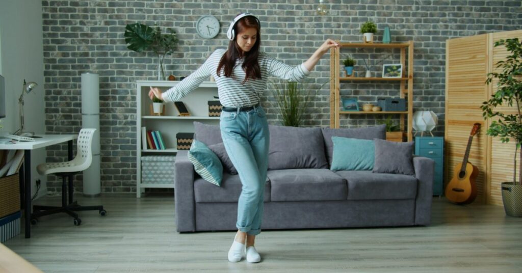 Young woman dancing to music playing on headphones
